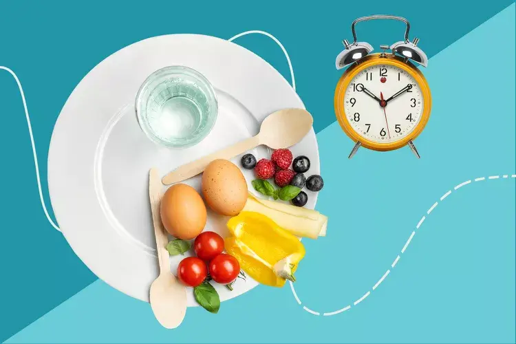 ظرفی سفید پر از میوه موز و گوجه و تخم مرغ در کنارش یک ساعت برای برنامه رژیم فستینگ