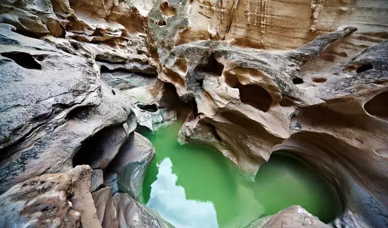 کوهی حفره دار با چشمه ای سبز رنگ