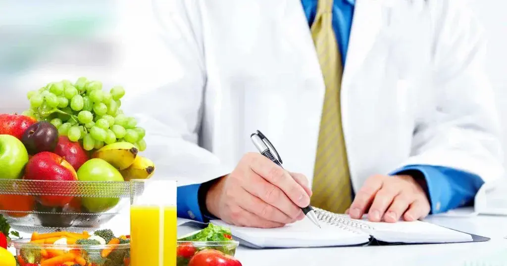 یک دکتر در حال نوشتن و میوه و آب میوه بر روی میزش