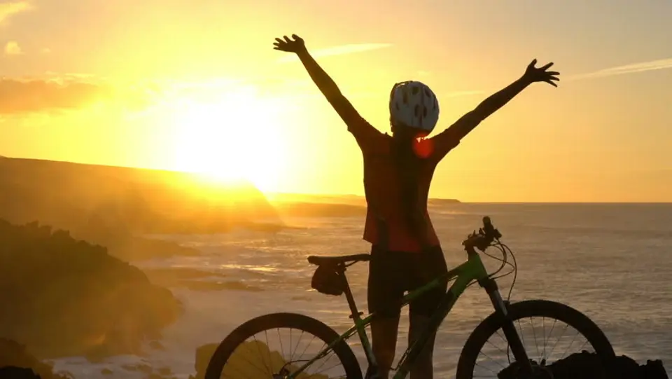 زنی با دوچرخه در غروب آفتاب