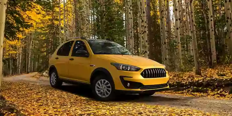 خودرو اطلس زرد رنگ در جاده پاییزی با برگ