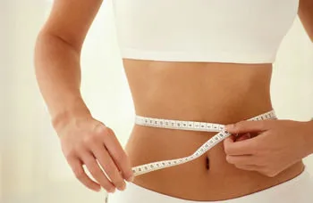 یک زن در حال اندازه گرفتن دور کمر برای لاغری شکم